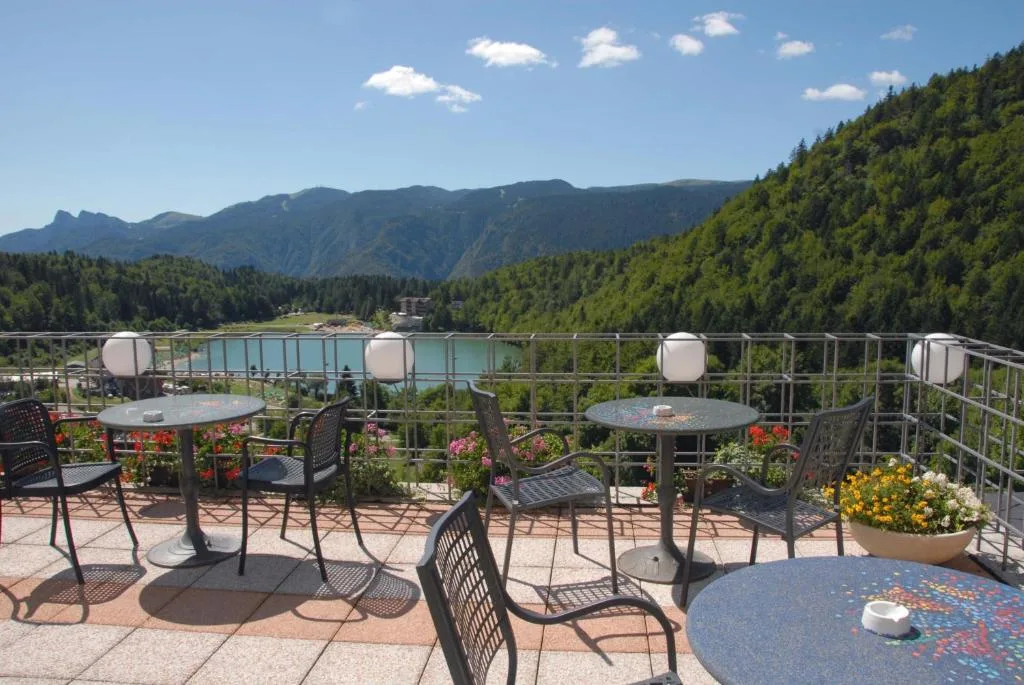 Terrazza con tavolini e sedie affacciata sul lago e sulle montagne