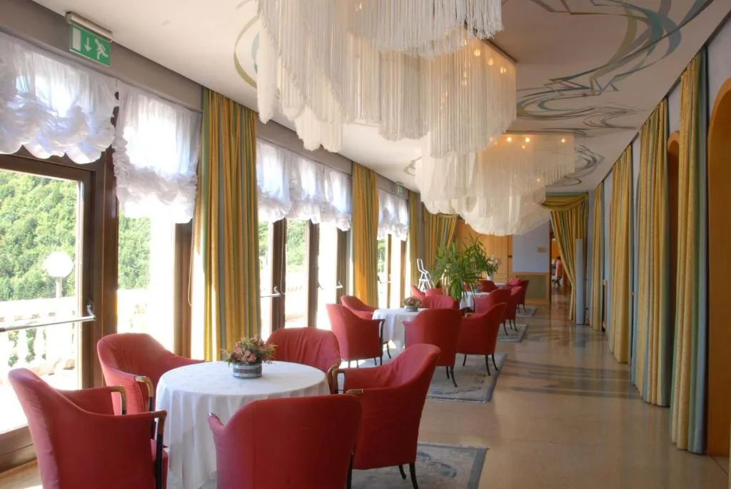 Sala soggiorno luminosa con poltrone rosse e grandi lampadari bianchi