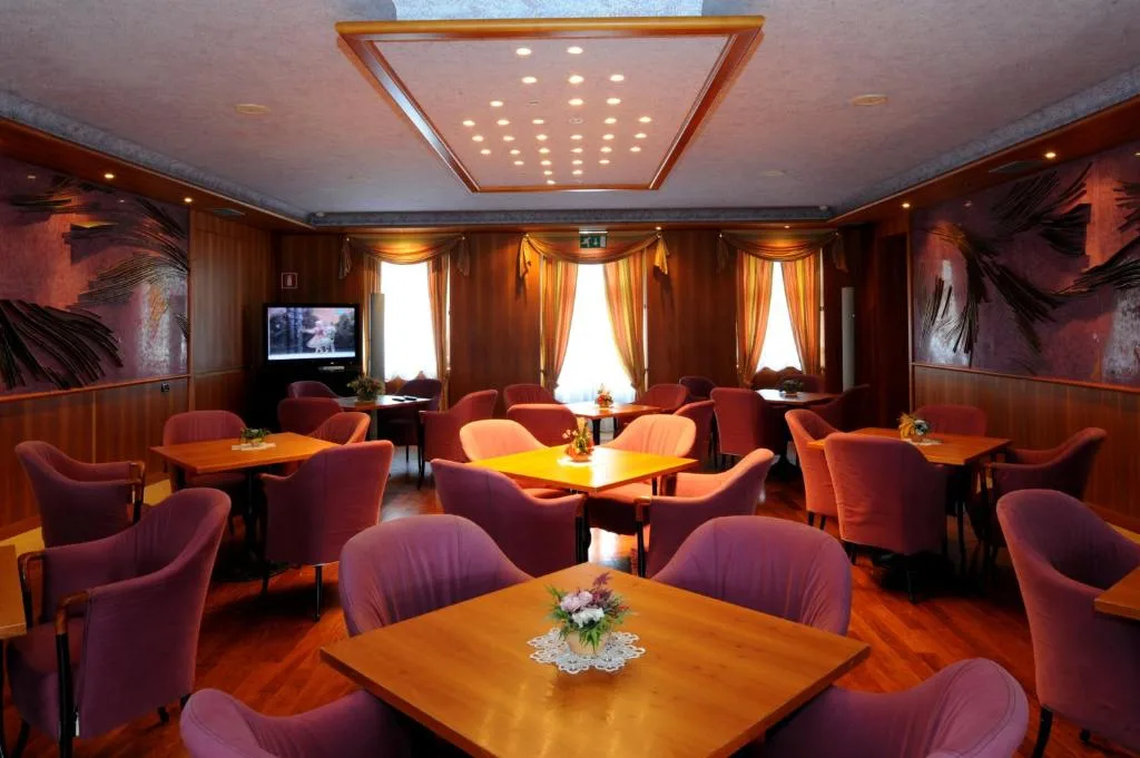 Sala lounge con poltrone rosa, tavoli in legno e TV