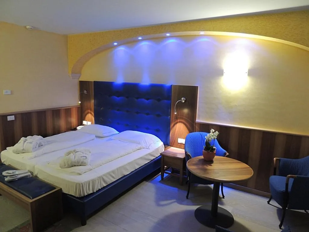 Camera elegante con testiera blu illuminata e accappatoi sul letto