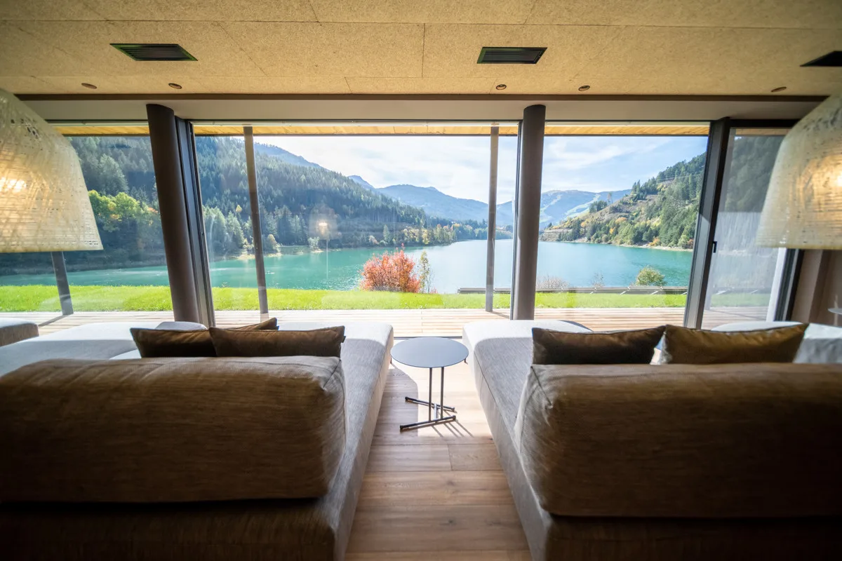 Sala relax con divani e vetrate panoramiche sul lago e sulle montagne