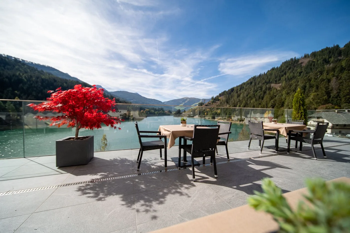 Terrazza esterna con tavoli, acero rosso e vista sul lago e sulle montagne