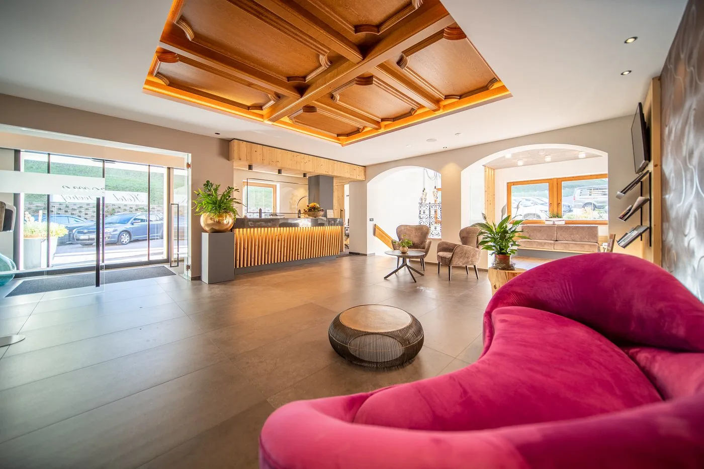 Hall dell'hotel con soffitto in legno, reception e divano rosa
