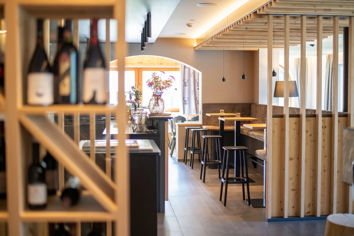 Zona bar con cantina dei vini e tavoli alti in ambiente in legno