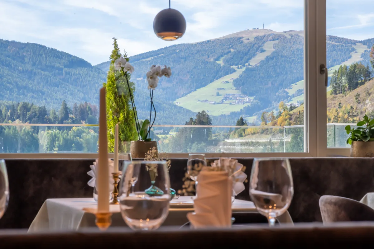 Tavolo del ristorante apparecchiato con vista sulle montagne dalla finestra