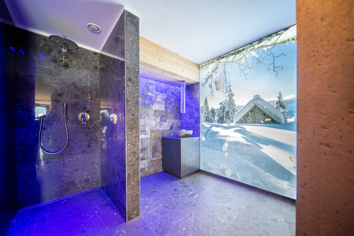 Doccia emozionale della spa con illuminazione blu e parete panoramica invernale