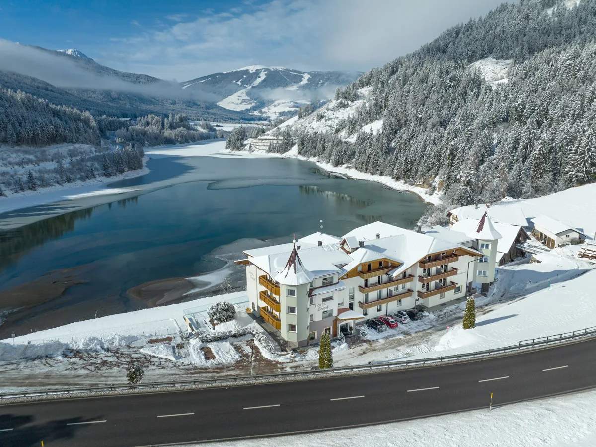 Vista aerea dell'Hotel Seehof innevato sul lago con strada e montagne