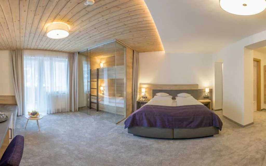 Camera spaziosa con letto matrimoniale, soffitto in legno e cabina in vetro