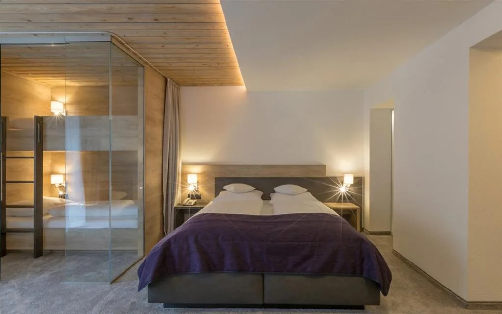 Camera moderna con letto matrimoniale, illuminazione soffusa e parete in vetro