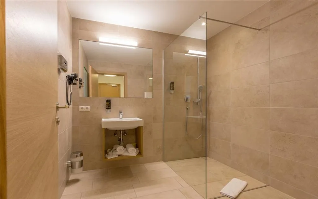 Bagno moderno con doccia a filo pavimento, lavabo e ampio specchio