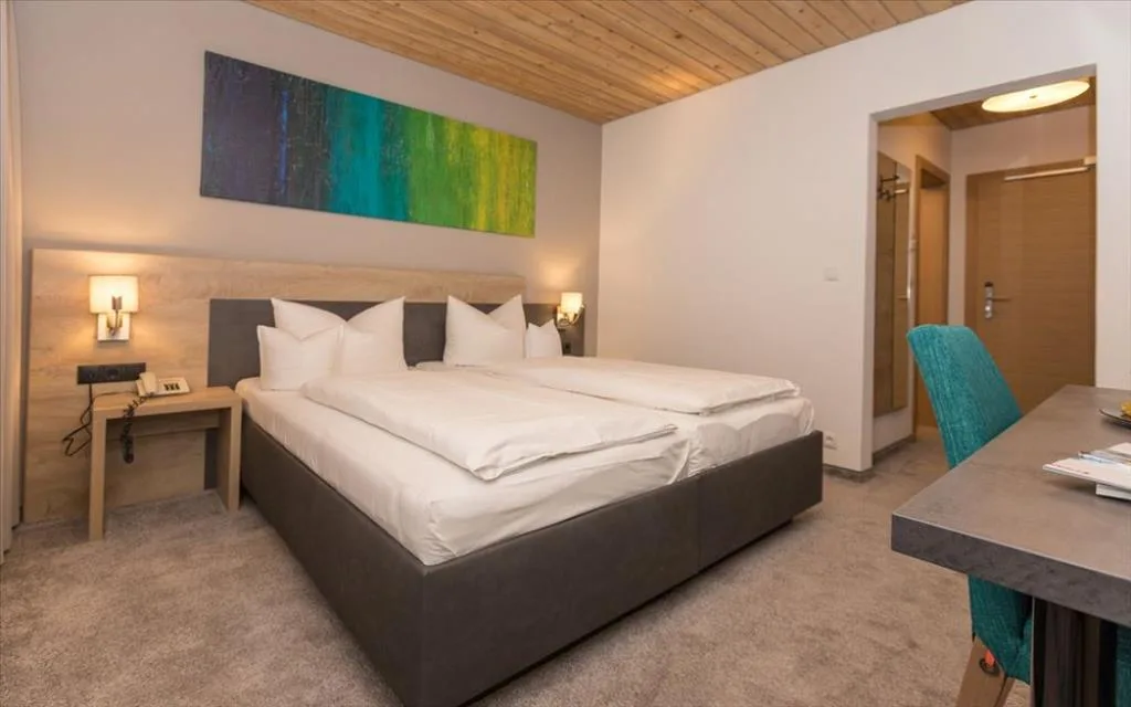 Camera doppia con letto, quadro colorato e scrivania con sedia turchese
