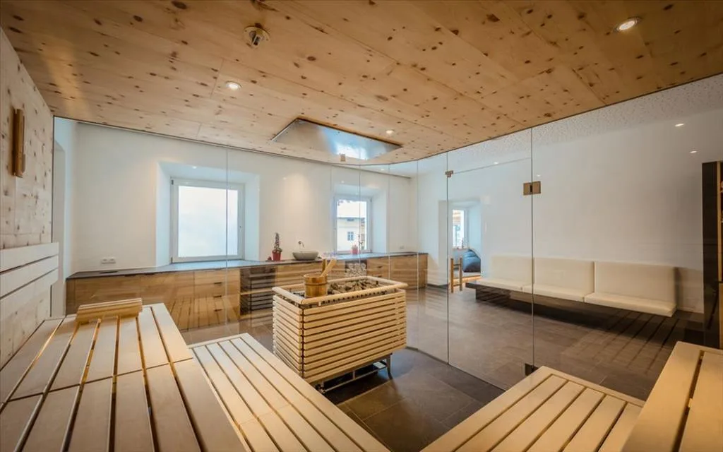 Sauna moderna in legno di cirmolo con pareti a specchio e panche