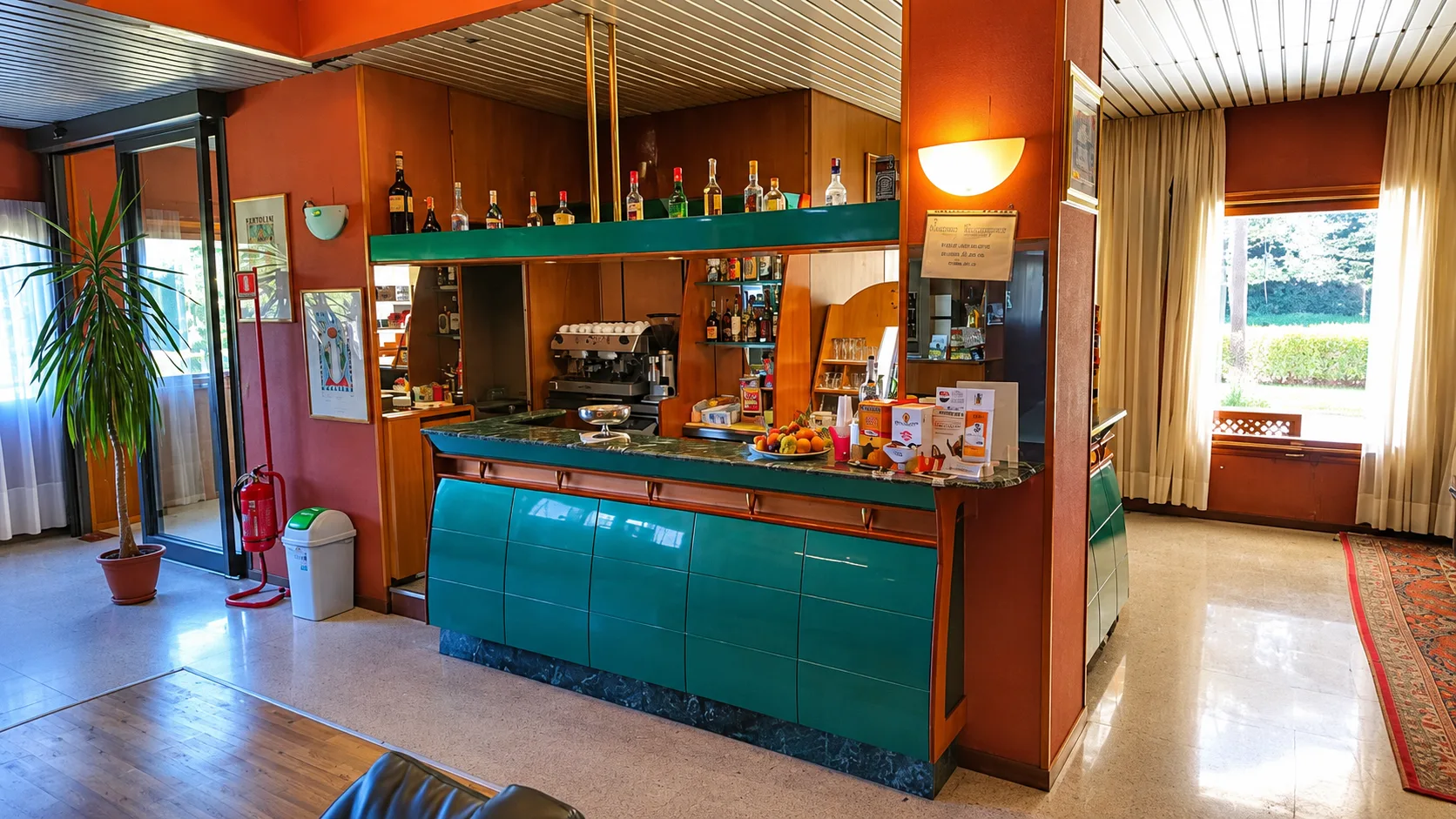 Area bar dell'hotel con bancone verde, bottiglie e macchina del caffè