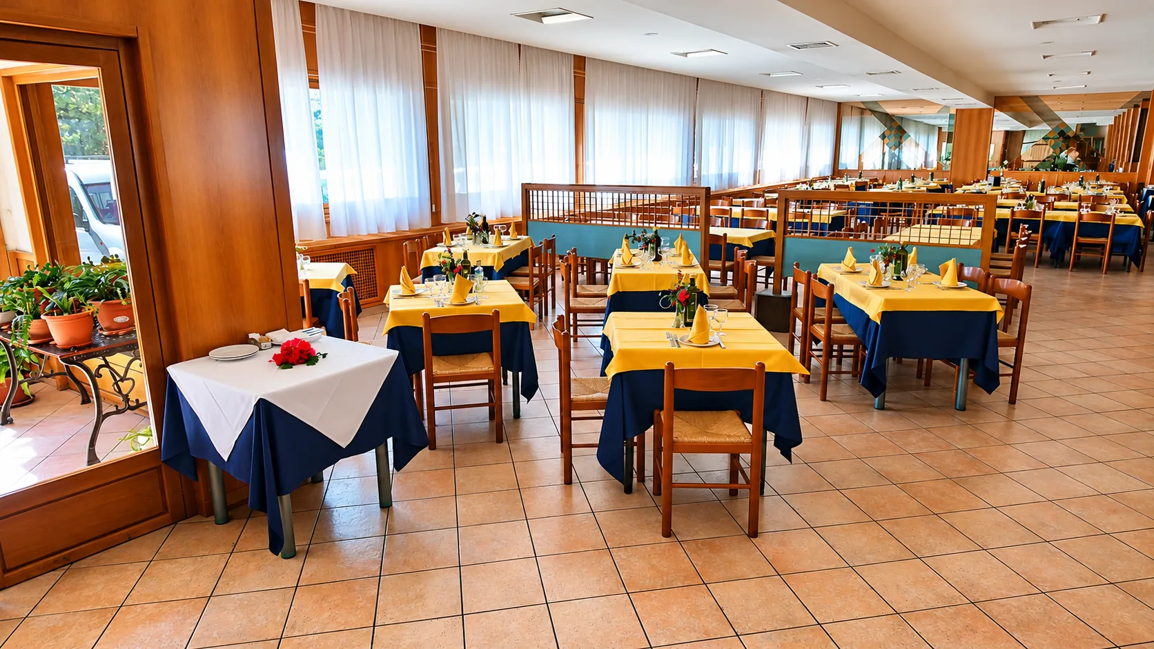 Sala ristorante con tavoli apparecchiati con tovaglie gialle e blu
