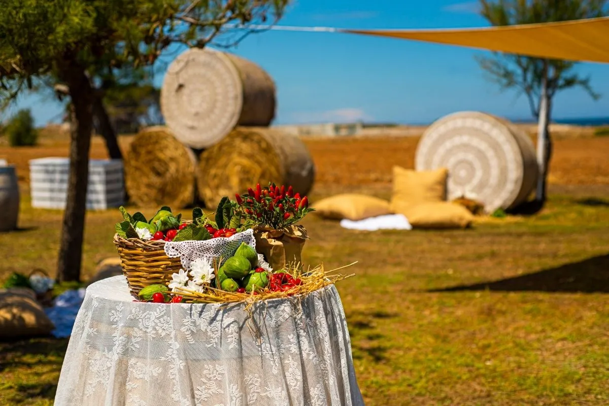 Allestimento rustico all'aperto con cesto di verdure e balle di fieno