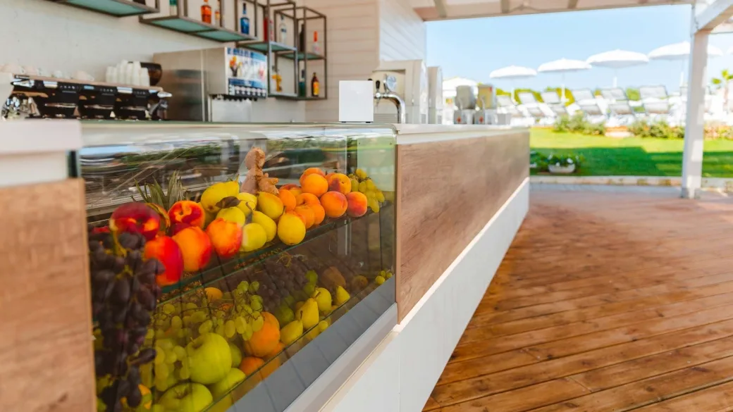 Bancone bar con vetrina di frutta fresca e vista sul solarium esterno