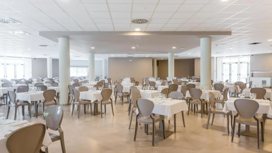 Ampia sala ristorante interna con tavoli apparecchiati e sedie moderne
