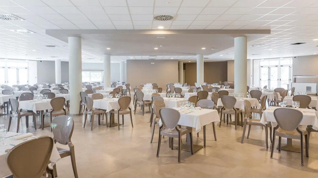 Sala ristorante interna luminosa con tavoli apparecchiati e sedie