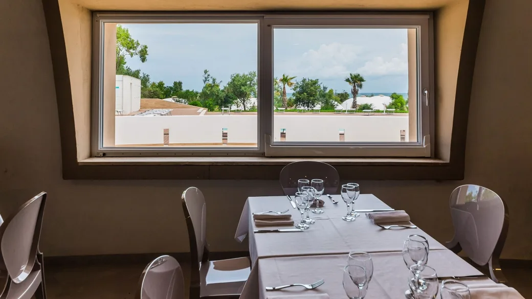 Tavolo apparecchiato del ristorante con vista sul giardino e mare dalla finestra