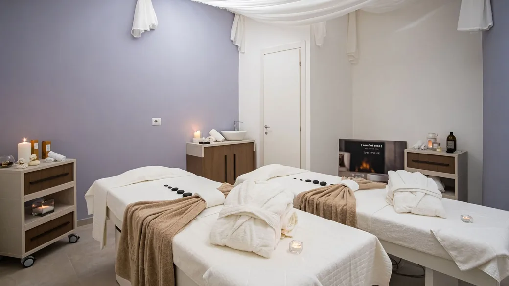 Sala massaggi della spa con lettini, accappatoi e candele in atmosfera rilassante