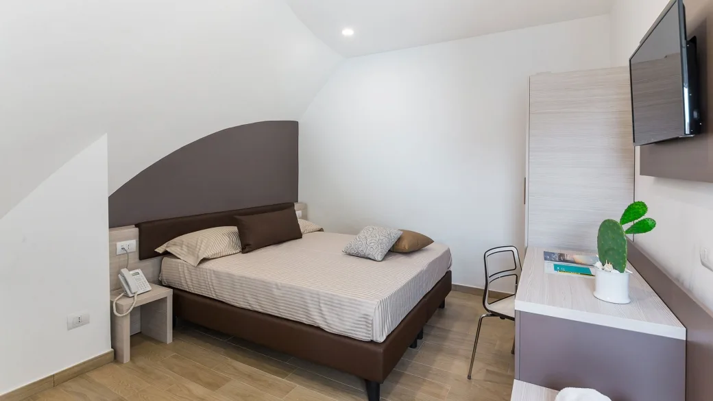 Camera matrimoniale con letto, TV a parete e scrivania in stile moderno