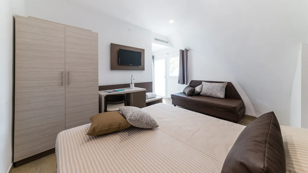 Camera con letto matrimoniale, divano, TV e accesso esterno