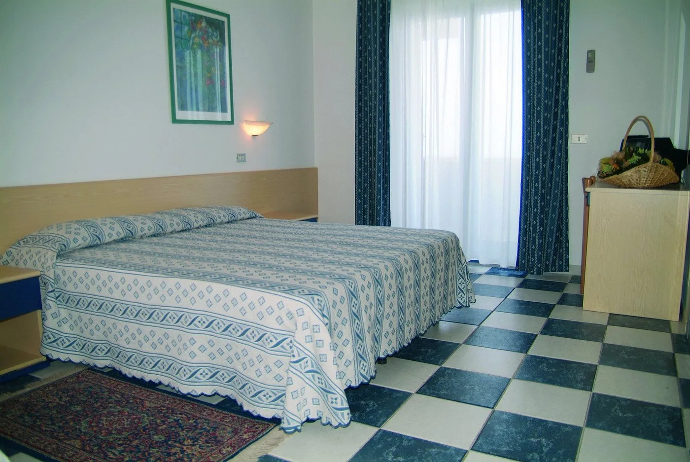 Camera matrimoniale con letto, tende blu e pavimento a scacchi