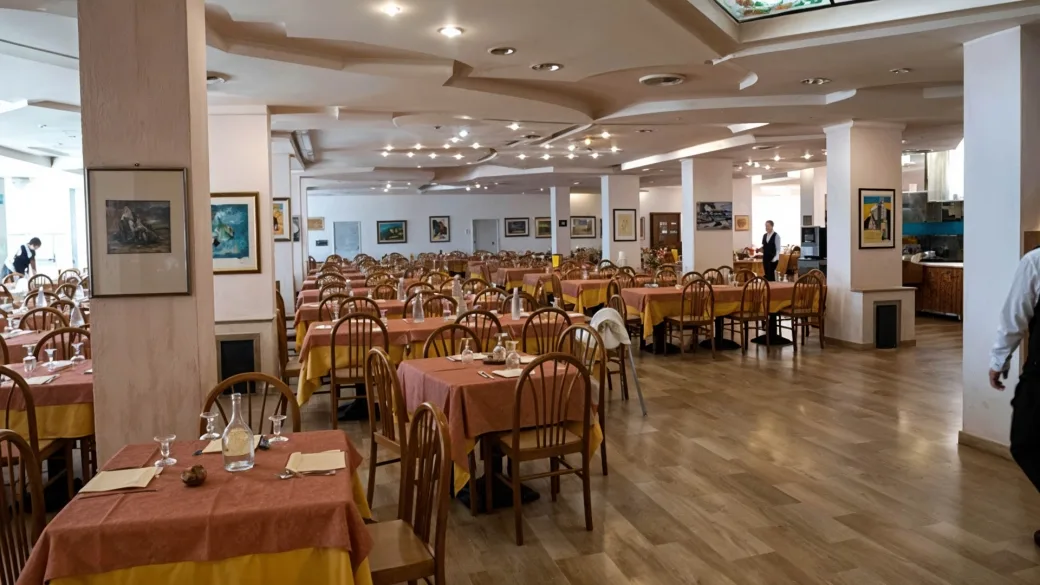 Ampia sala ristorante con tavoli apparecchiati, tovaglie colorate e quadri alle pareti