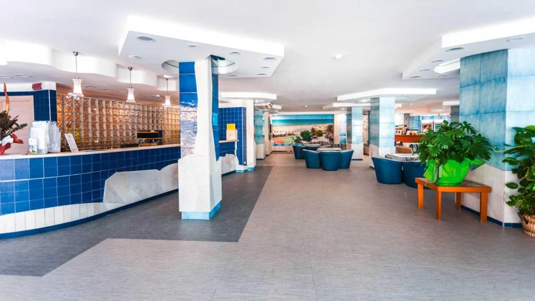 Hall dell'hotel con reception in mosaico blu, poltrone e ambienti luminosi