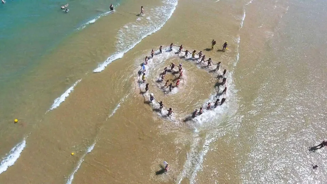 Animazione in acqua sulla spiaggia con partecipanti disposti in cerchio vista dall'alto