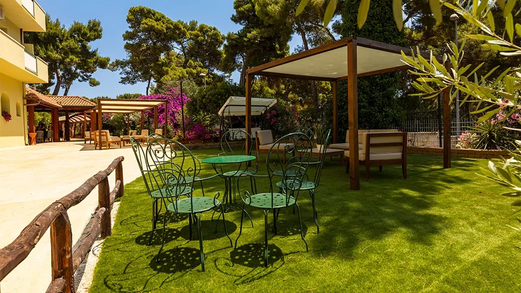 Giardino verde con tavolini, gazebo e vegetazione fiorita