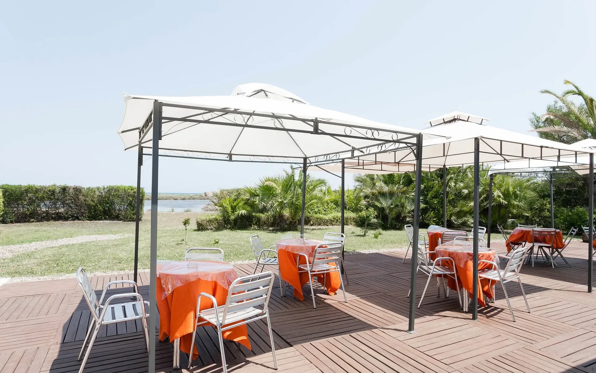 Gazebo esterno con tavoli, sedie e vista su giardino e laguna