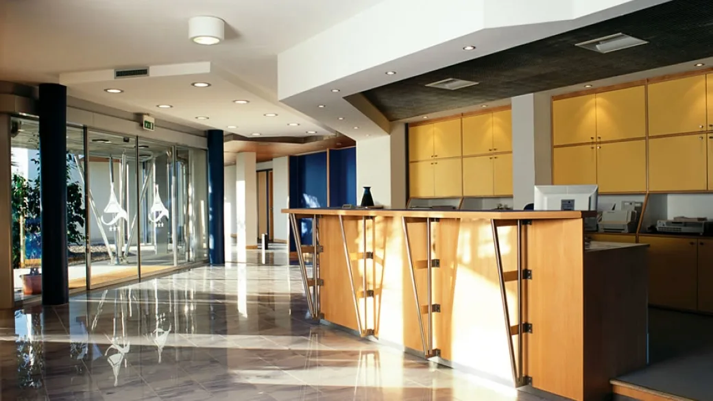 Reception dell'hotel con bancone in legno moderno e pavimento lucido