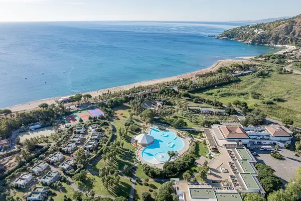 Panoramica aerea del villaggio turistico con piscina, campi sportivi e spiaggia sul mare