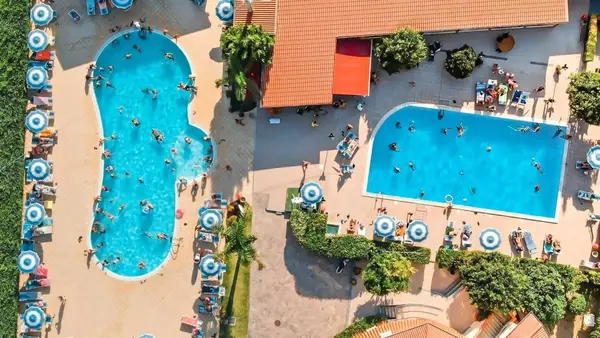 Vista dall'alto di due piscine con ombrelloni a righe e bagnanti