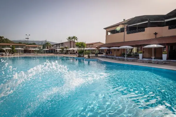 Piscina con giochi d'acqua e zona idromassaggio accanto all'edificio principale del resort