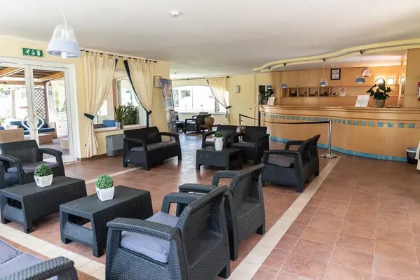 Hall reception con poltrone in rattan scuro e bancone in legno