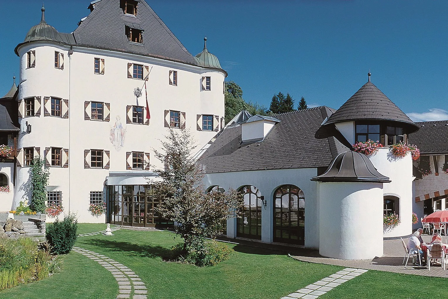 Facciata del castello bianco con torri e giardino curato