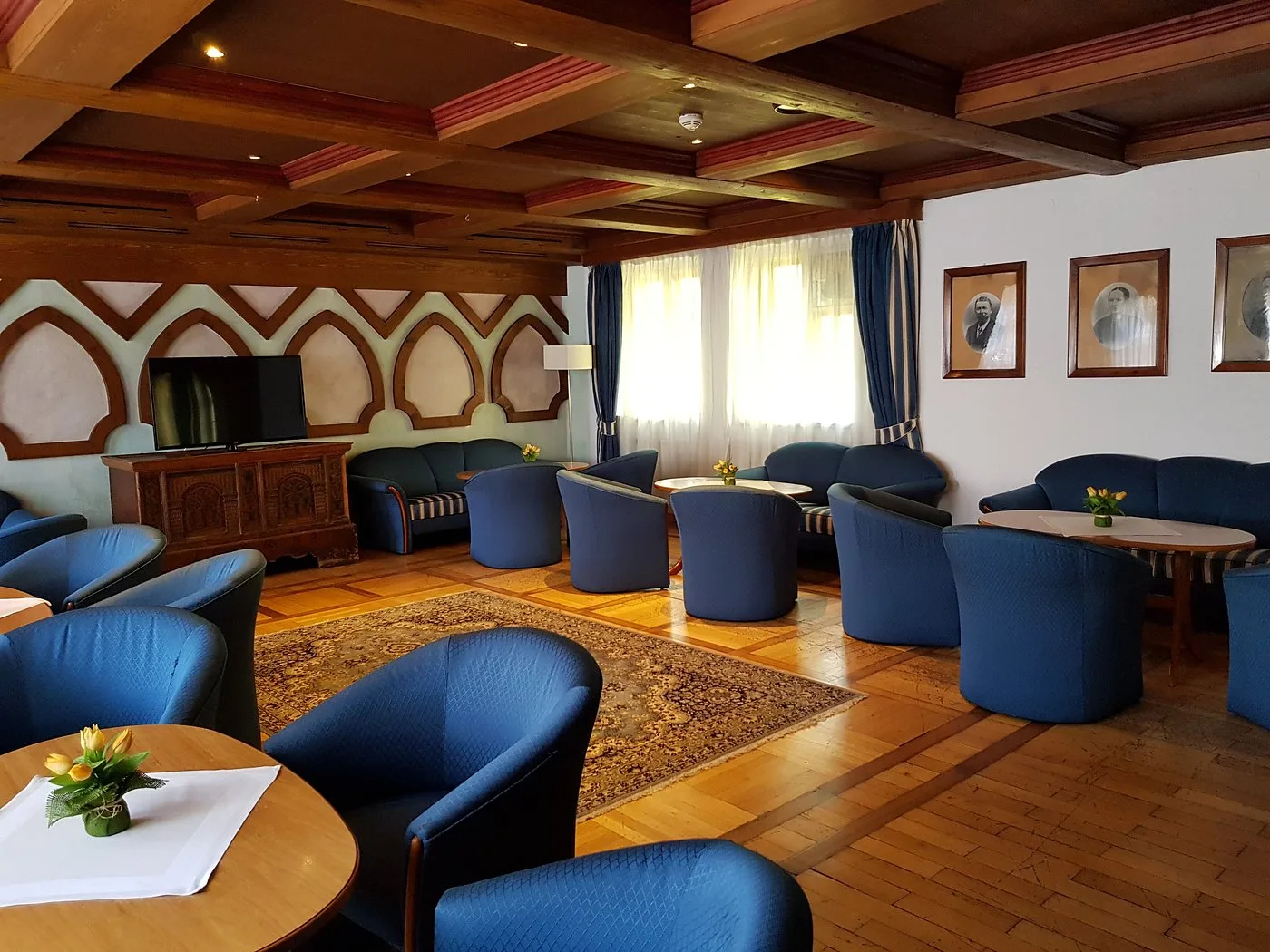 Salotto con poltrone blu, soffitto in legno e TV