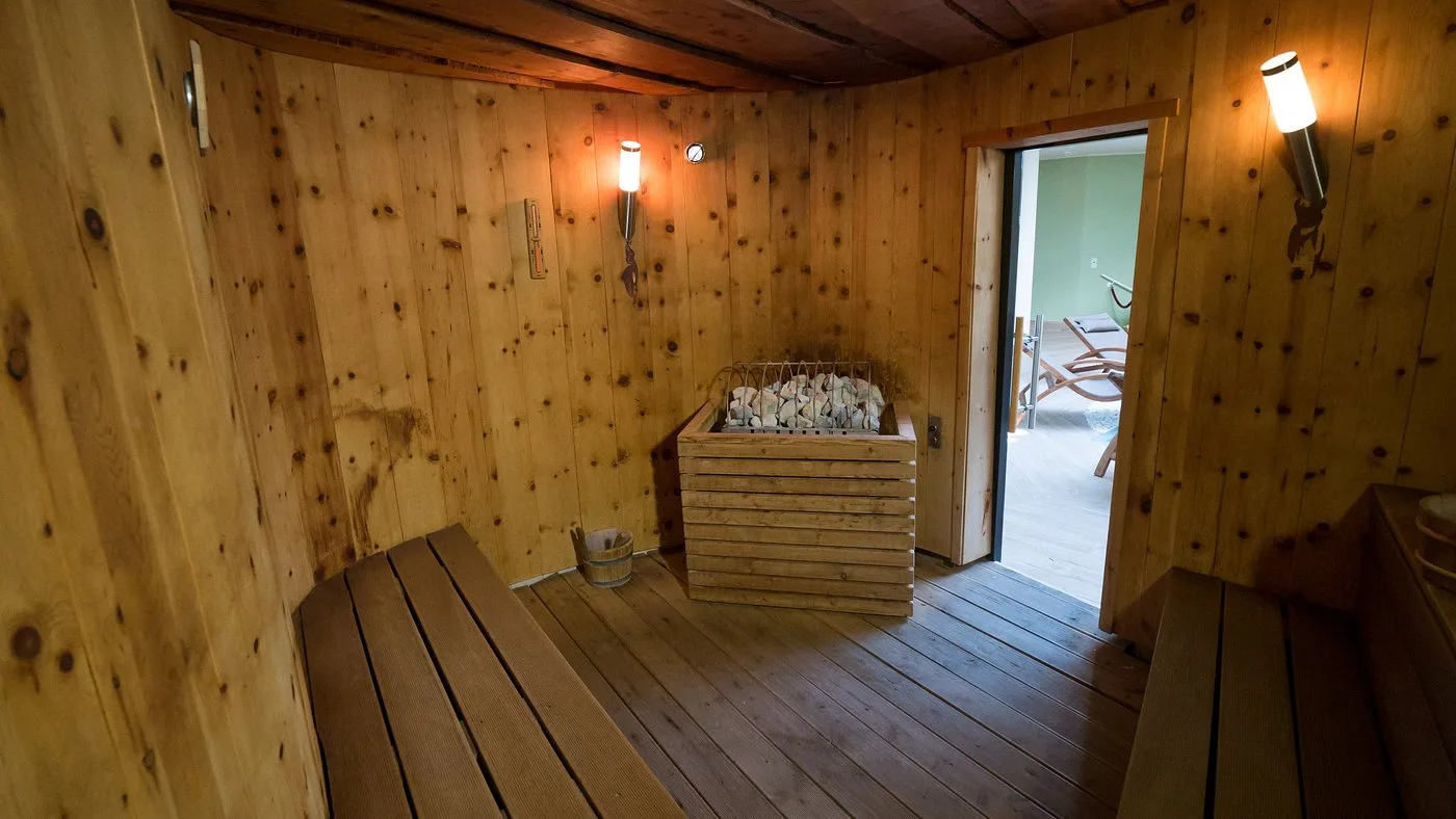 Sauna finlandese in legno con stufa e panche