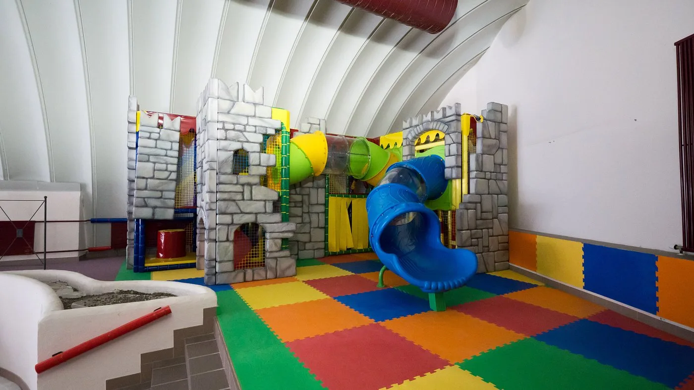 Area giochi per bambini a tema castello con scivoli e tappeti colorati