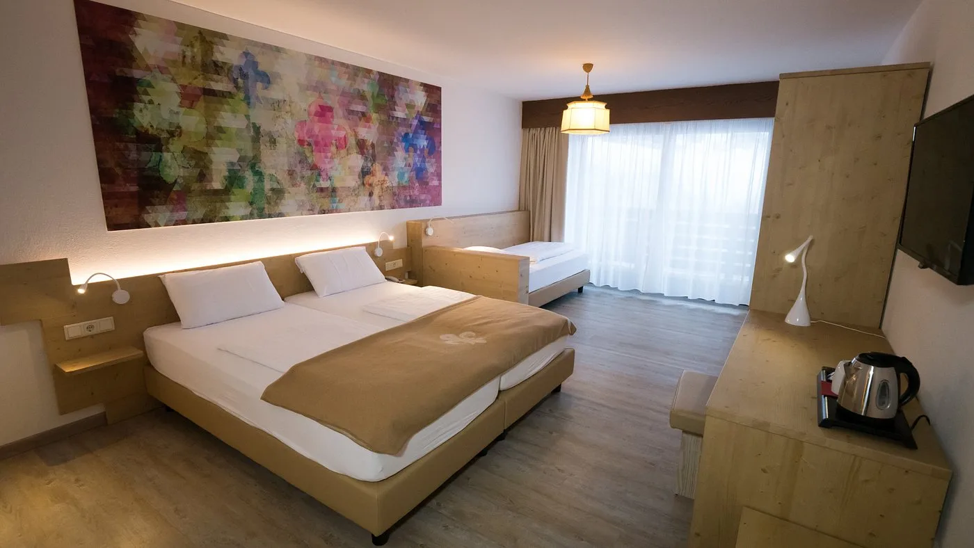 Camera con letto matrimoniale e singolo, arredo in legno chiaro