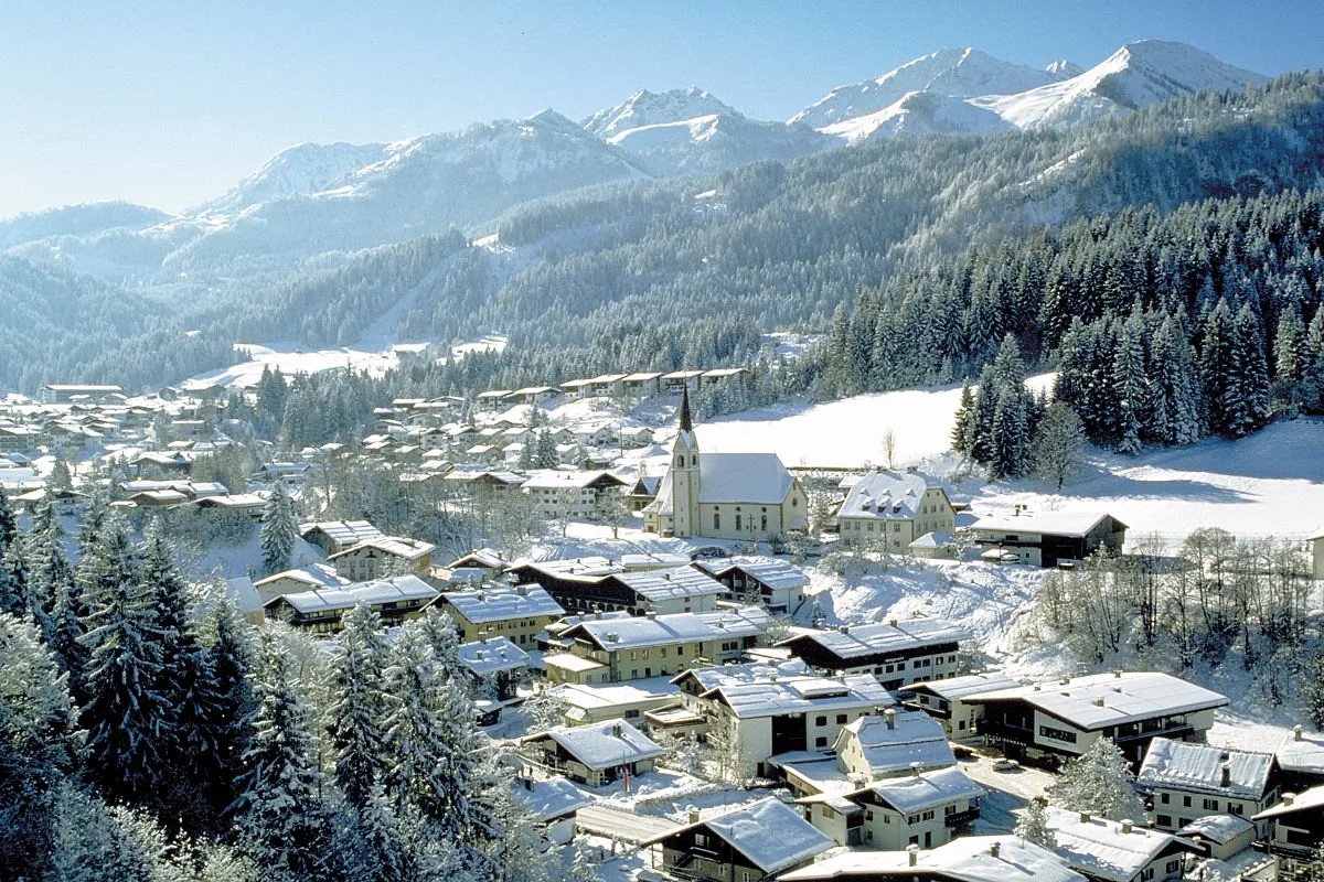 Veduta invernale del villaggio alpino innevato con chiesa e montagne