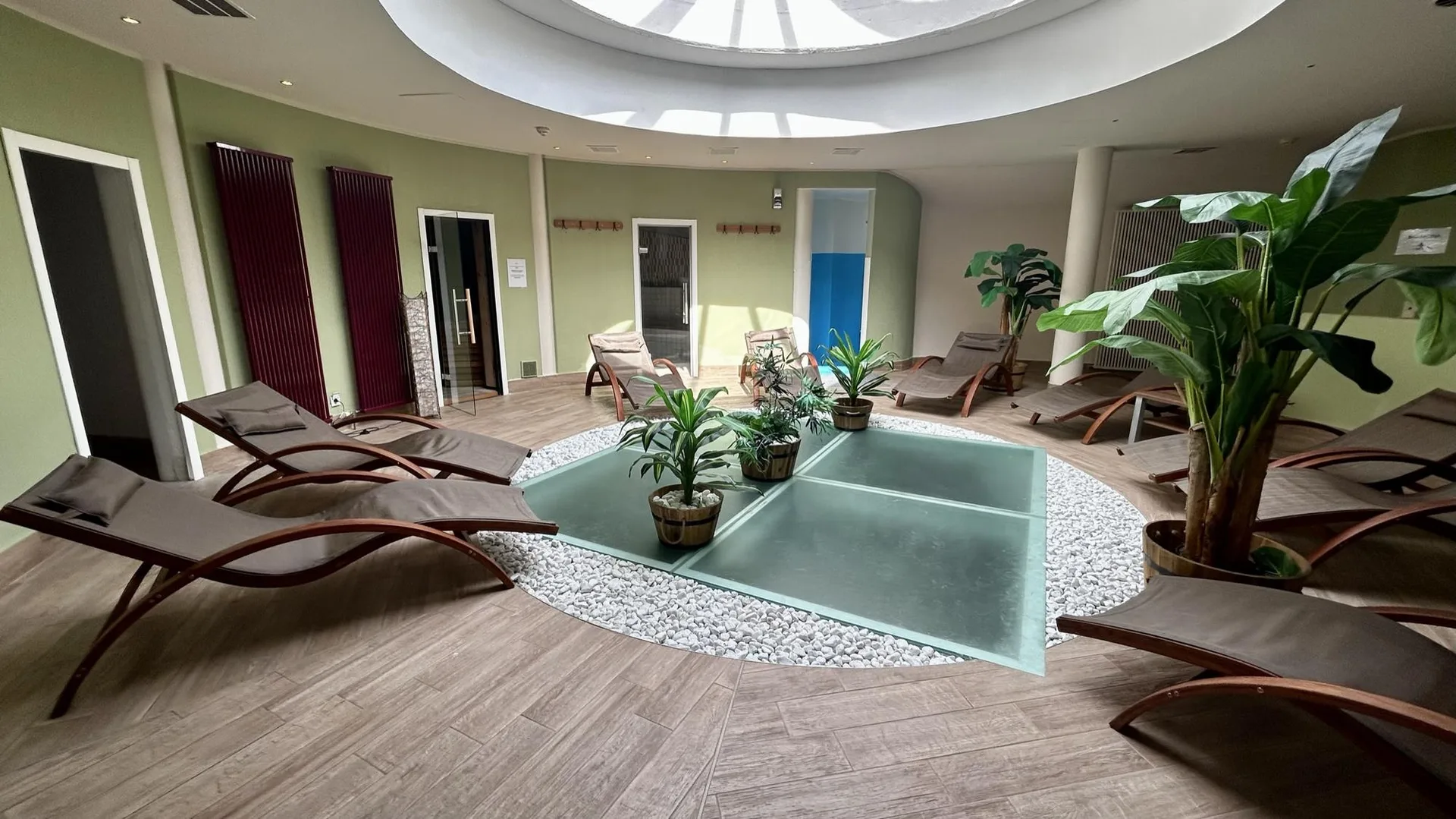 Area relax della spa con lettini e piante verdi sotto lucernario