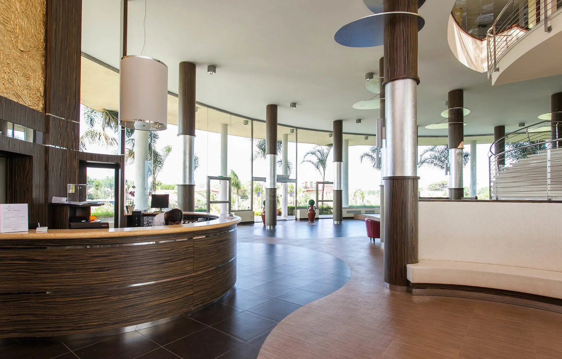 Hall del resort con reception curva in legno, colonne e ampie vetrate