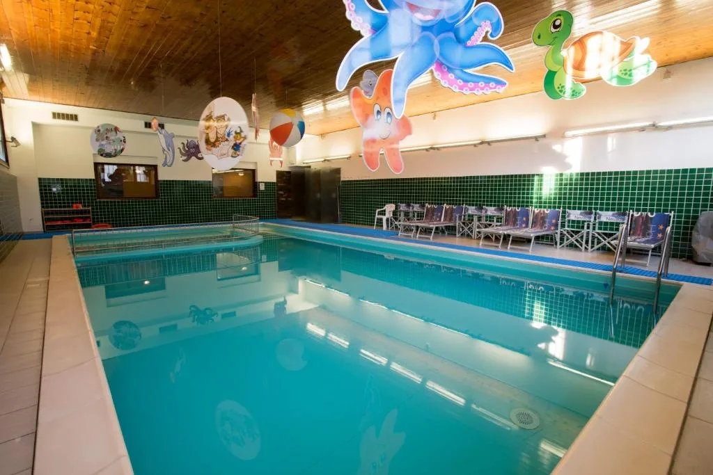 Piscina coperta per bambini con decorazioni marine colorate e lettini a bordo vasca