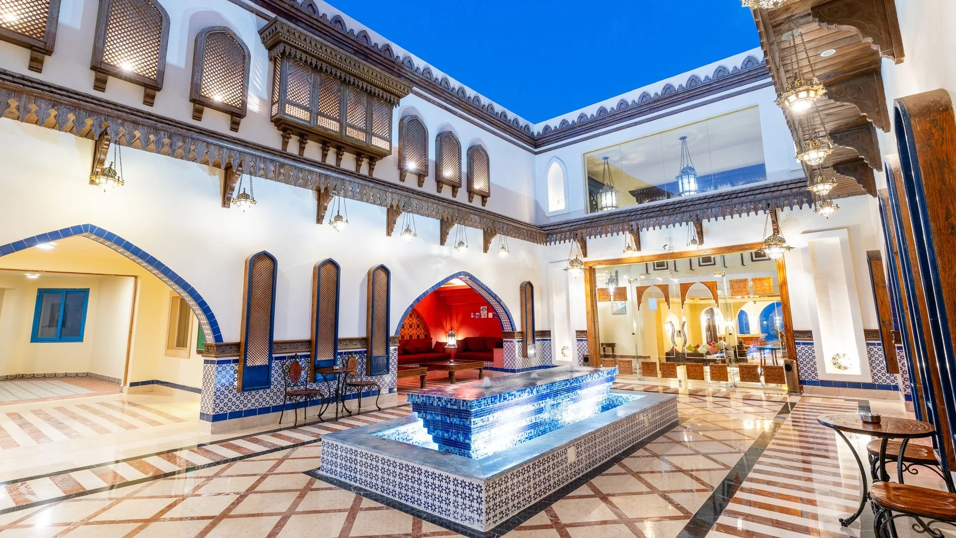Cortile interno in stile moresco con fontana a mosaico blu, archi e pavimento in marmo