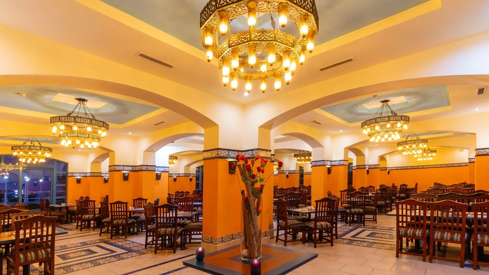 Sala ristorante con lampadari arabi dorati, colonne arancioni e tavoli in legno apparecchiati