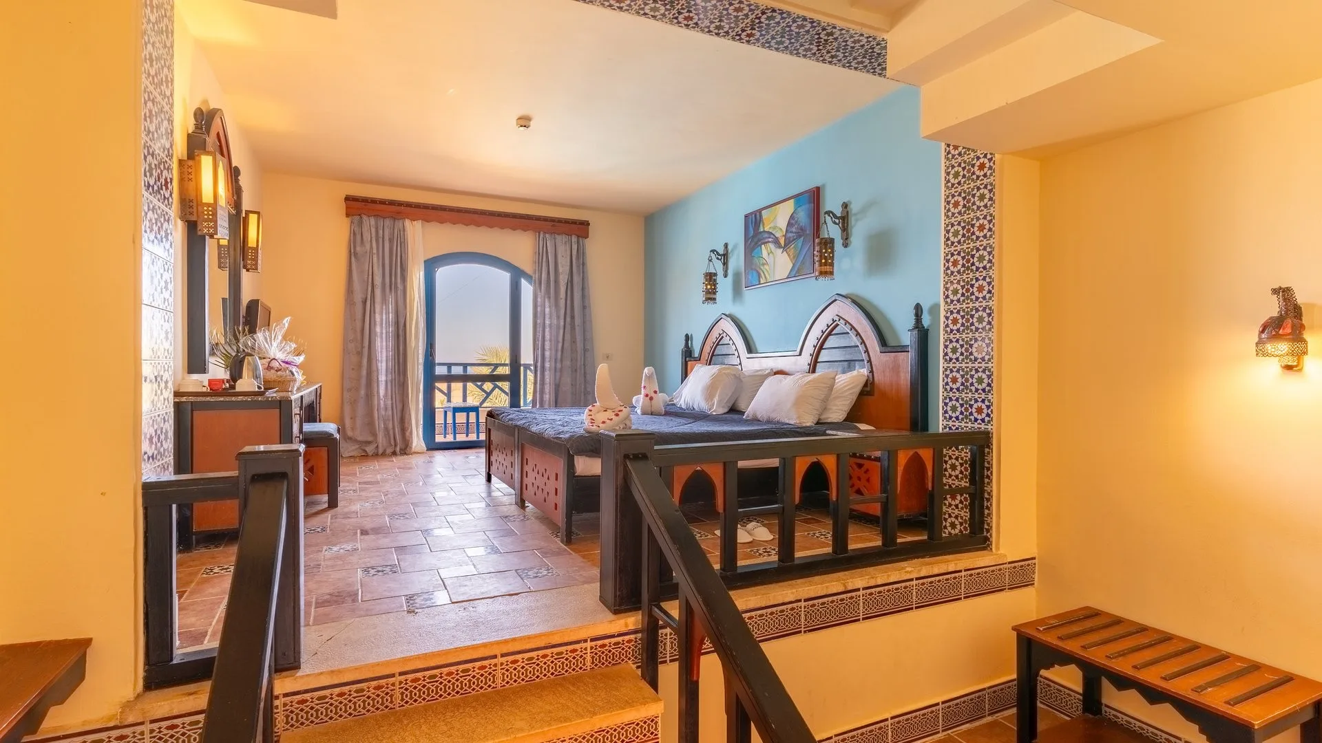 Camera in stile moresco con letto matrimoniale, testiera in legno decorata e balcone con vista
