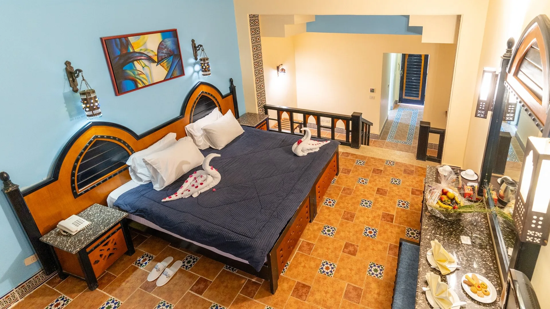 Camera soppalcata con letto matrimoniale, testiera decorata e pavimento con piastrelle a mosaico
